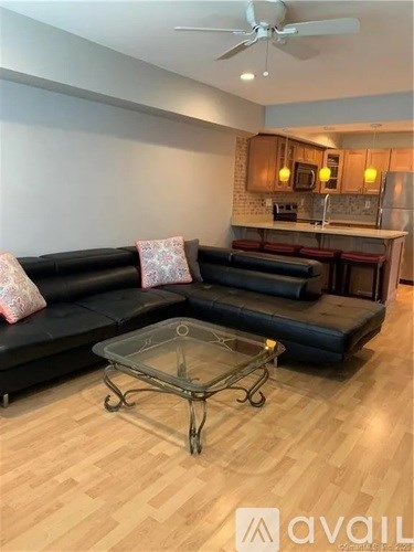 A living room with a black couch and a glass coffee table.