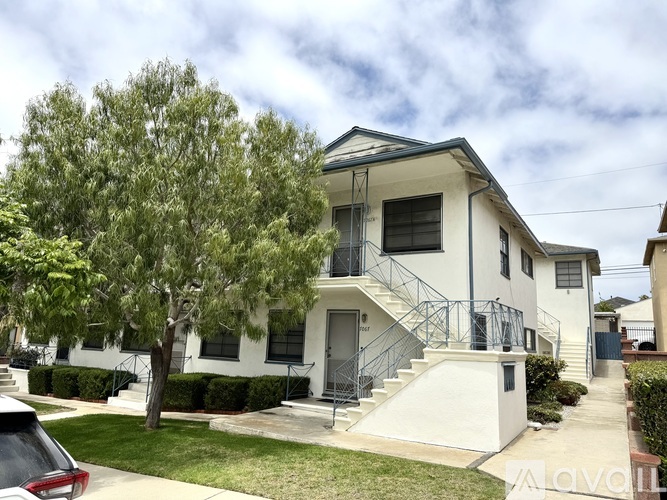 A two-story house with a white exterior and a balcony on the second floor.