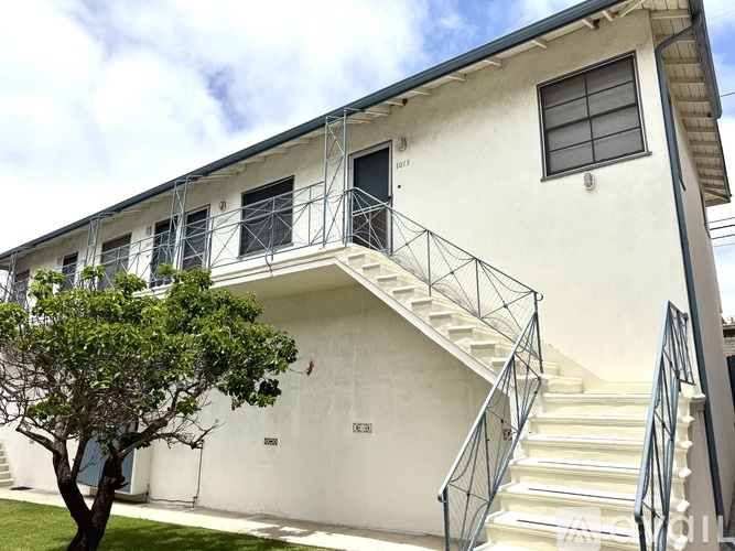 A white building with a tree in front of it.