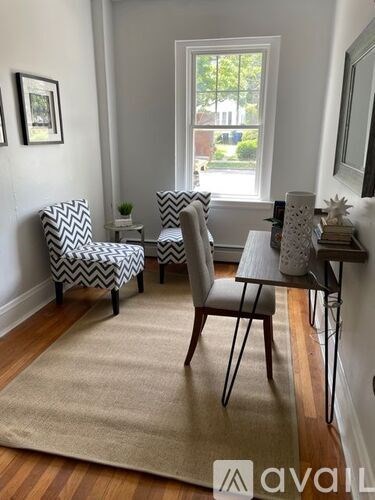 A living room with a chevron patterned chair and a small table with a vase on it.