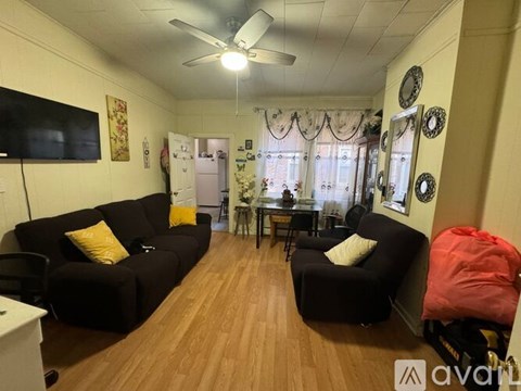 A living room with a black couch, a television, and a ceiling fan.