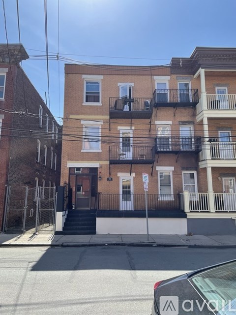 A building with a brown door and a balcony with a black railing.