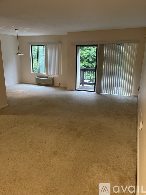 A large empty room with a window and sliding glass doors leading to a balcony.