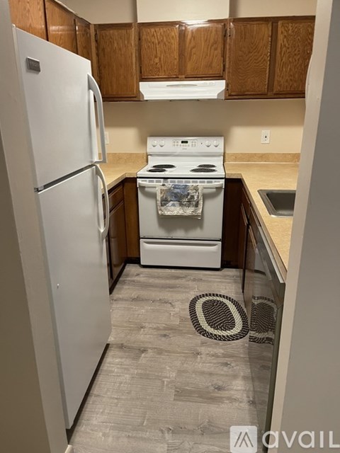 A kitchen with a white fridge, white stove and wooden cabinets.