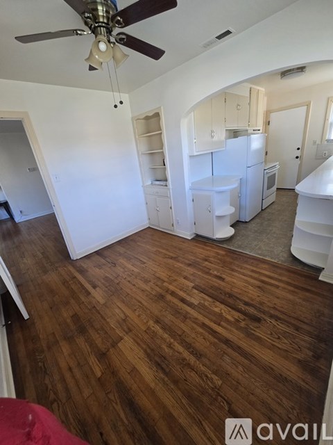 A kitchen with white appliances and wooden floors.