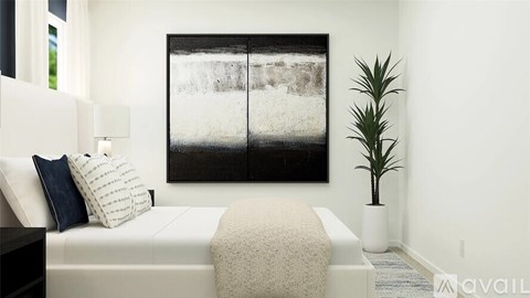 A bedroom with a large bed, a potted plant, and a large picture on the wall.