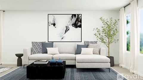 A living room with a white couch, a black coffee table, and a large abstract painting on the wall.