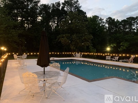 A pool area with chairs and umbrellas is lit up at dusk.