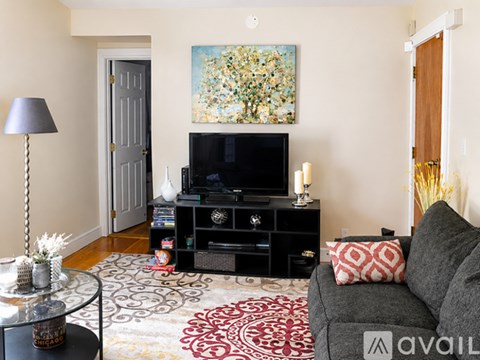 A living room with a grey couch, a coffee table, a television, and a painting on the wall.