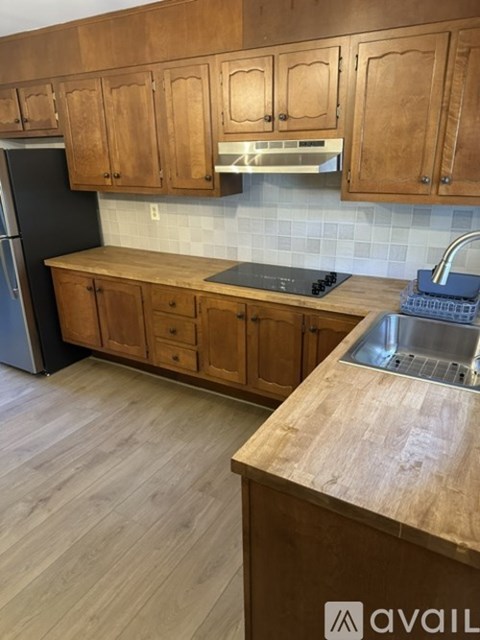 A kitchen with wooden cabinets and a black refrigerator.