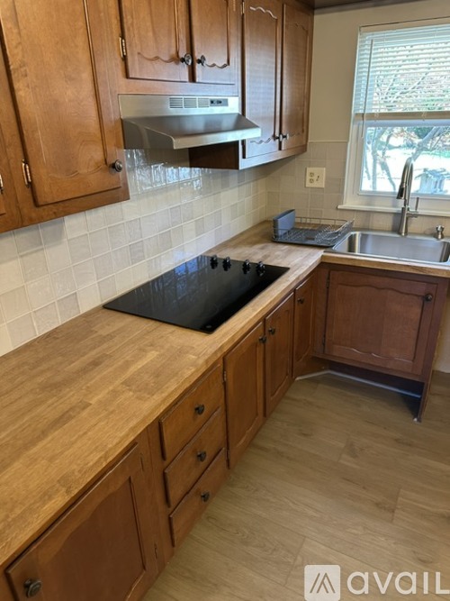 A kitchen with wooden cabinets and a black cutting board on the counter.