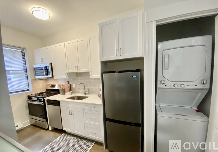 A kitchen with white cabinets and a black fridge.