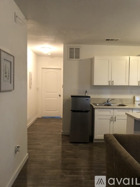 A kitchen with white cabinets and a fridge.