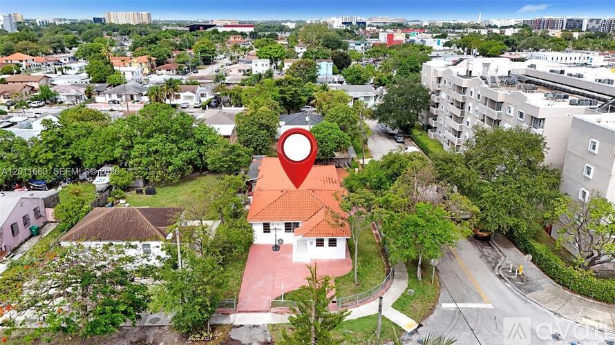 A red house with a white roof is located in the middle of a green area.
