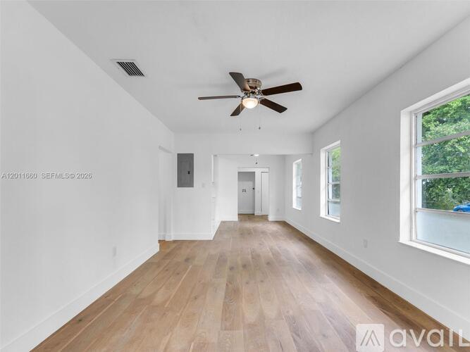 A spacious room with a ceiling fan and wooden flooring.