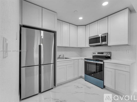 A modern kitchen with white cabinets and a black refrigerator.