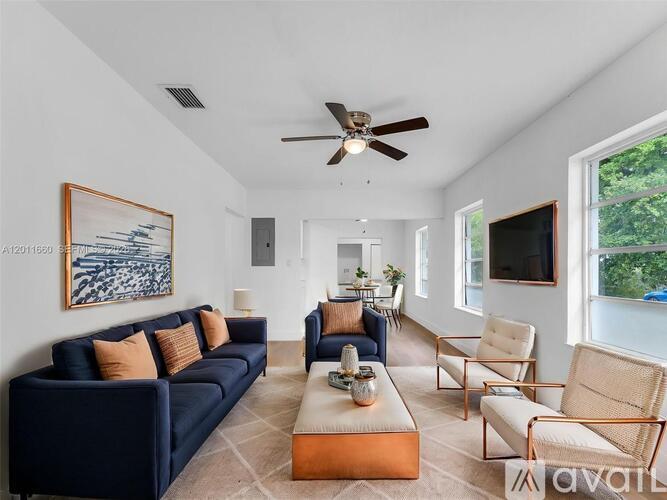 A living room with a dark blue couch, a coffee table, and a ceiling fan.