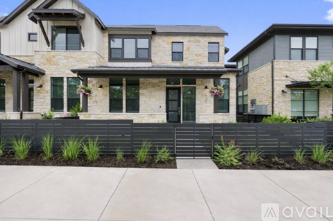 A modern house with a stone facade and a black fence.