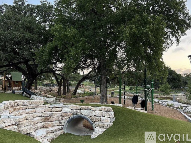A playground with a slide and a tunnel in the middle of a grassy area.
