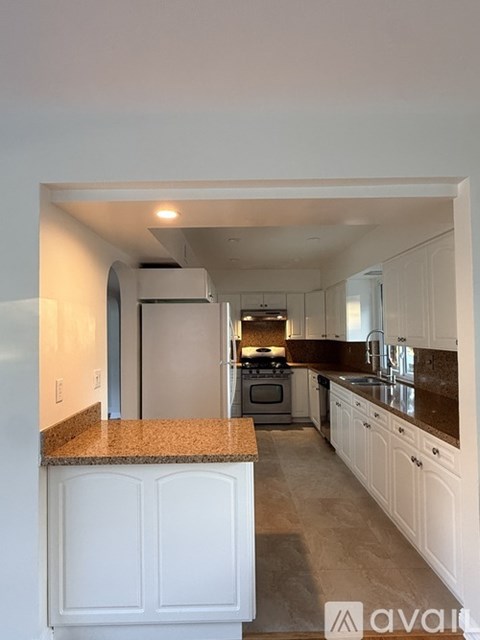 A kitchen with white cabinets and a granite countertop.
