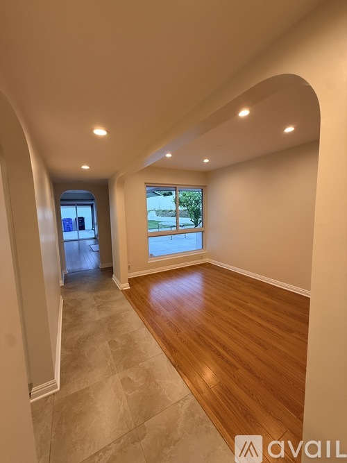 A spacious room with wooden flooring and a large window.