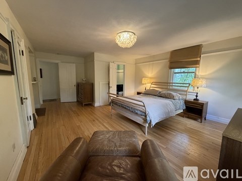 A bedroom with a large bed and a brown leather couch.