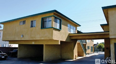 A yellow building with a green roof and a car parked in front.
