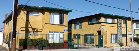 Two yellow houses with green trim and a black fence in front.