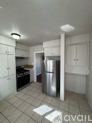 A kitchen with white cabinets and a stainless steel refrigerator.