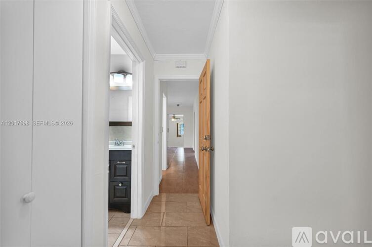A hallway with a wooden door leading to another room.