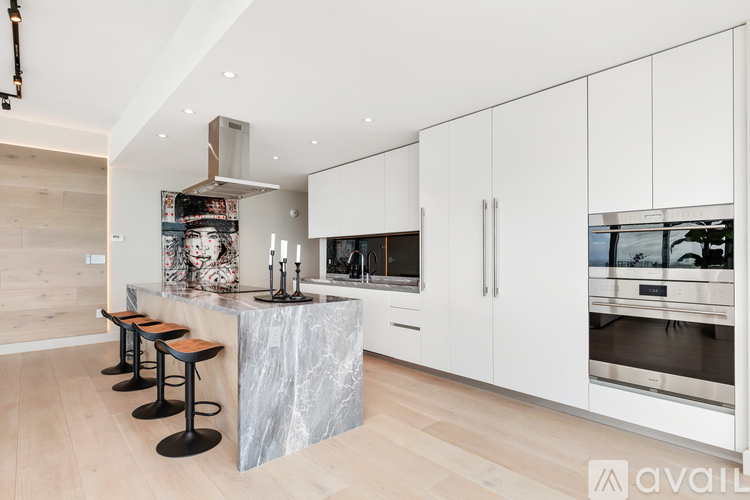 A kitchen with white cabinets and a marble island.
