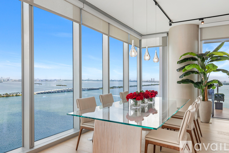 A dining room with a glass table and chairs with a view of the water.
