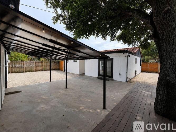 A patio area with a black pergola and a tree in the foreground.