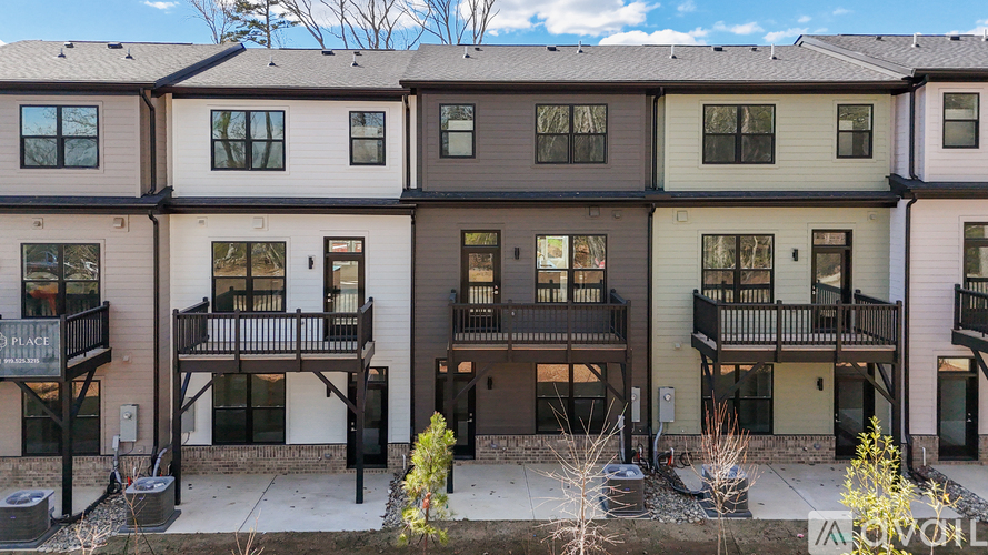 A row of townhouses with balconies and front yards.