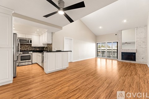 A spacious kitchen with white cabinets and a black ceiling fan.