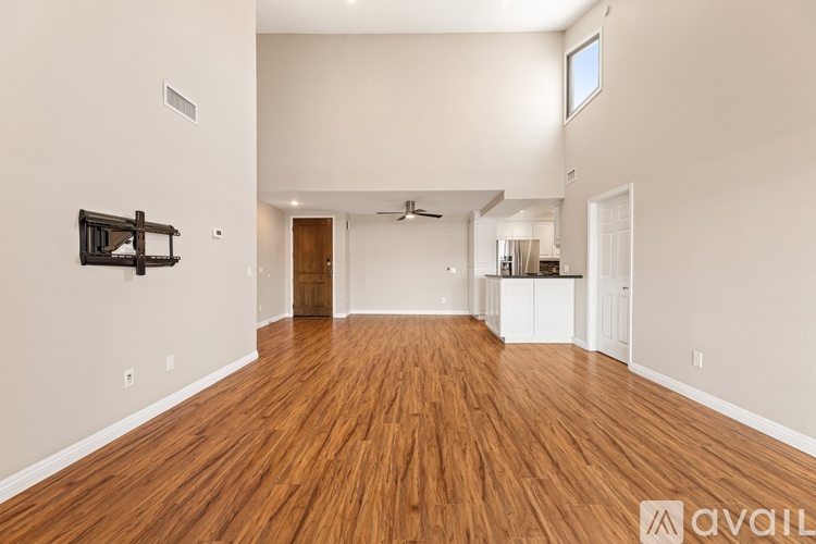A spacious room with wooden flooring and a ceiling fan.