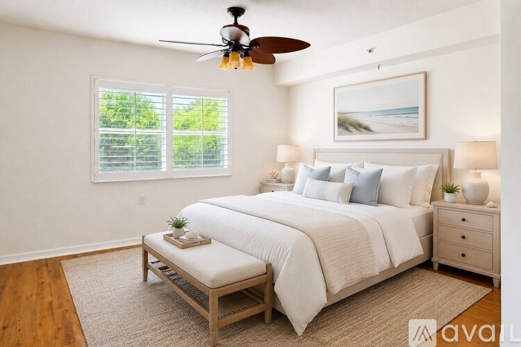 A bedroom with a large bed, a ceiling fan, and a window with blinds.