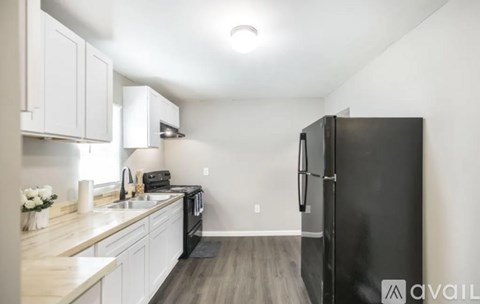 A kitchen with a black refrigerator and white cabinets.