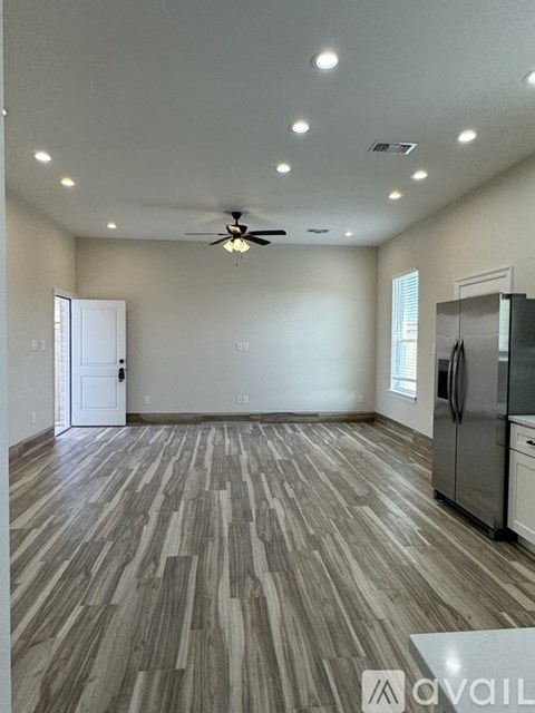 A spacious room with a ceiling fan and wooden flooring.