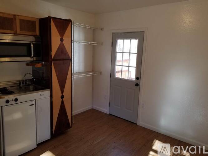 A kitchen with a white oven and microwave, a white door, and a brown cabinet.