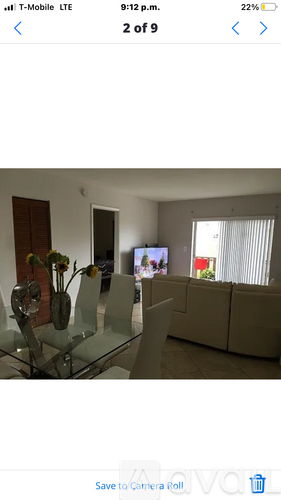 A living room with a glass table and a TV in the background.
