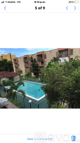 A pool surrounded by trees and apartment buildings.