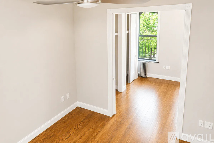 A room with a fan and wooden floors.