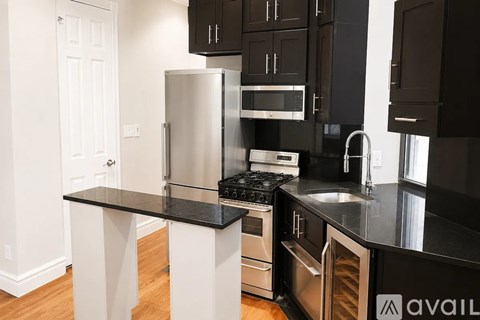 A kitchen with black countertops and stainless steel appliances.