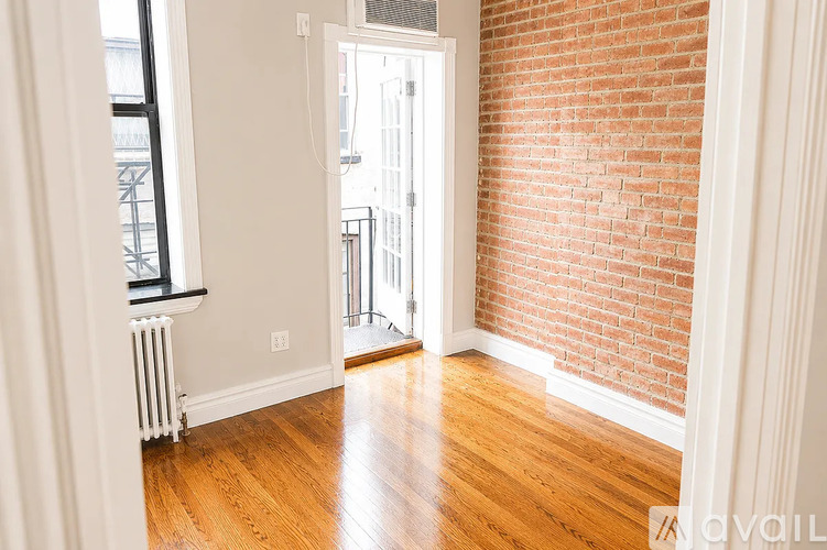 A room with a wooden floor and a brick wall.