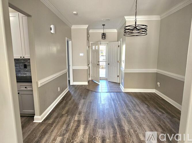 A hallway with wood flooring and white walls.