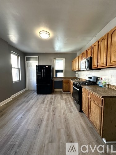 A kitchen with wooden cabinets and a black fridge.