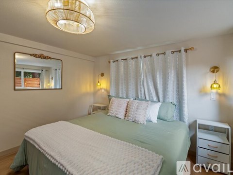 A bedroom with a bed, nightstand, and a mirror on the wall.