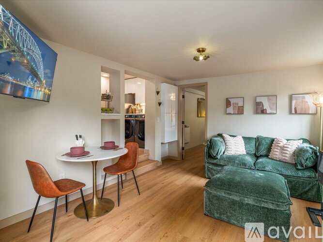 A living room with a green couch and a dining table with chairs.