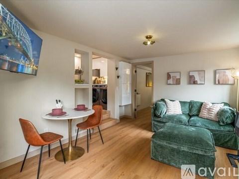 A living room with a green couch and a dining table with chairs.